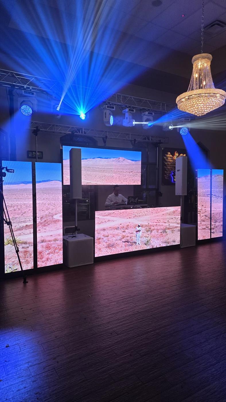Moving-head fixtures on truss throwing blue beams across a ballroom